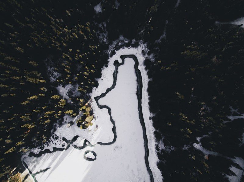 a drone shot of a zigzagging river near a forest on a winters day, aerial view of winding river 4k