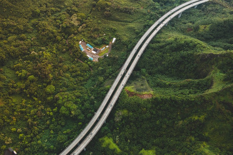 a drone shot of a two lane road on forested hills, elevated two lane road 4k