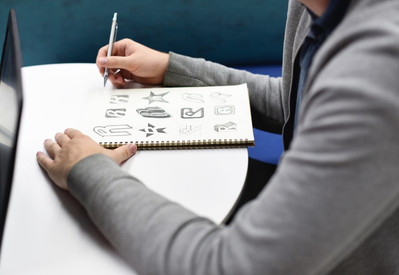 a person designing brand logos in a sketchbook, brand logo designer 4k