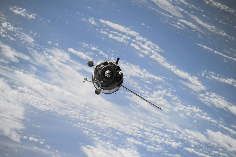 a satellite with a solar panel in orbit over the cloudy skies, satellite in orbit 4k