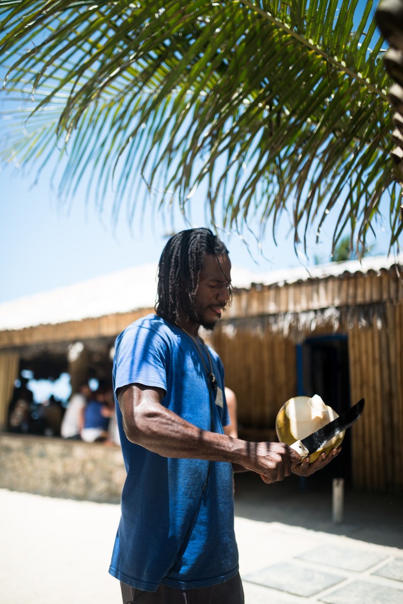 a man cuts a coconut outside a stand in ocho rios, man cutting a coconut 4k