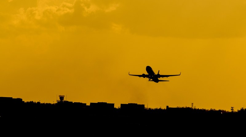 a silhouette of an airplane against an orange sky over an airport, launching 4k