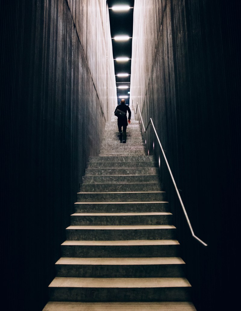 a lone man with a handbag climbing high stairs, man with a handbag on stairs 4k