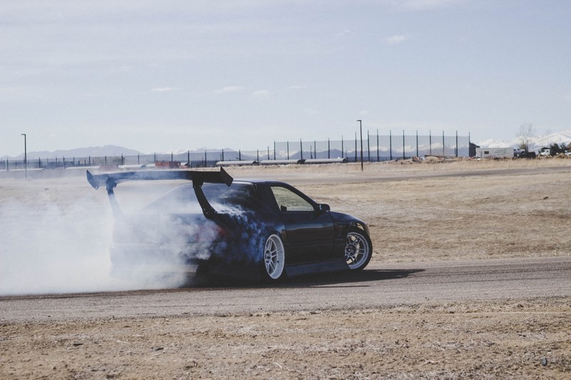 race car driving on road with dust and exhaust, tires shredded 4k