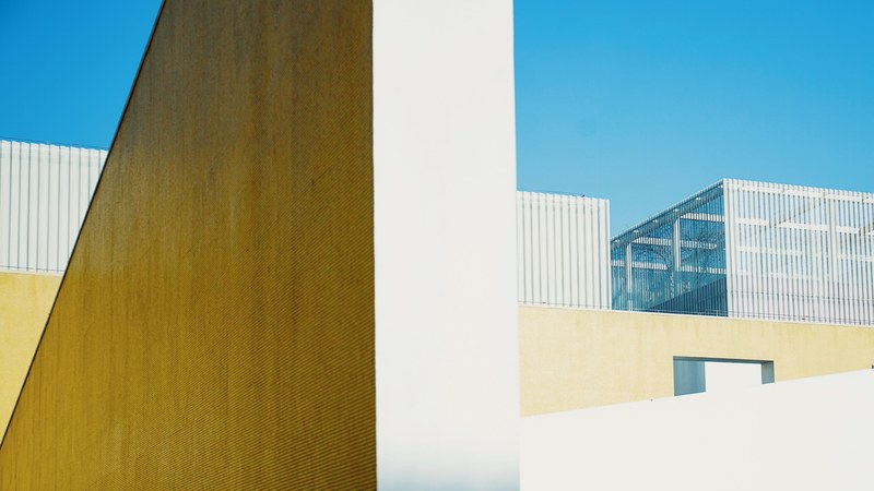 the yellow facade of a building in qingpu under a blue sky, minimal yellow and blue facade 4k