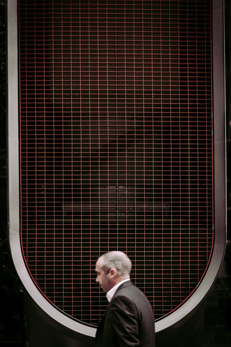 a low angle shot of a man in a black suit under a grid on the roof, man in city 4k