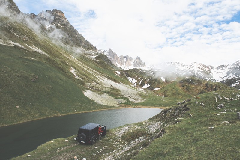 jeep truck parked on the side of a river valley near picturesque mountains, stopping in the wilderness 4k