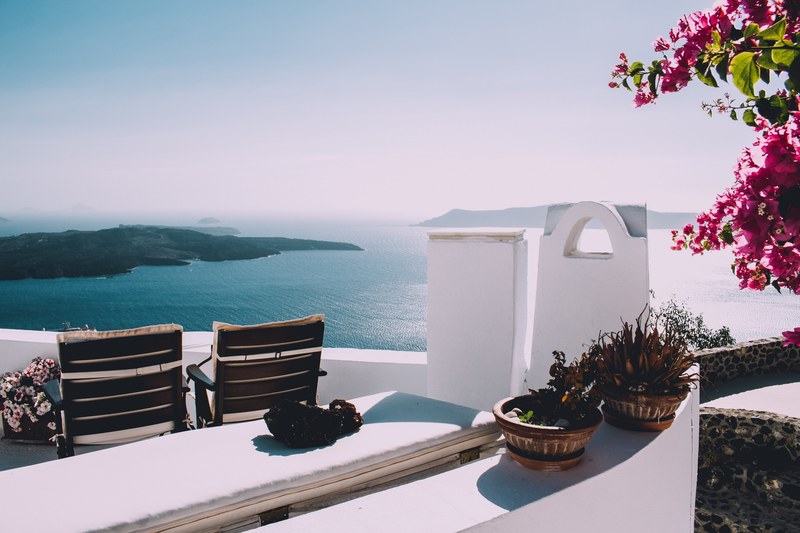 two empty deck chairs on a white mediterranean balcony overlooking the vast sea, vacation in greece 4k