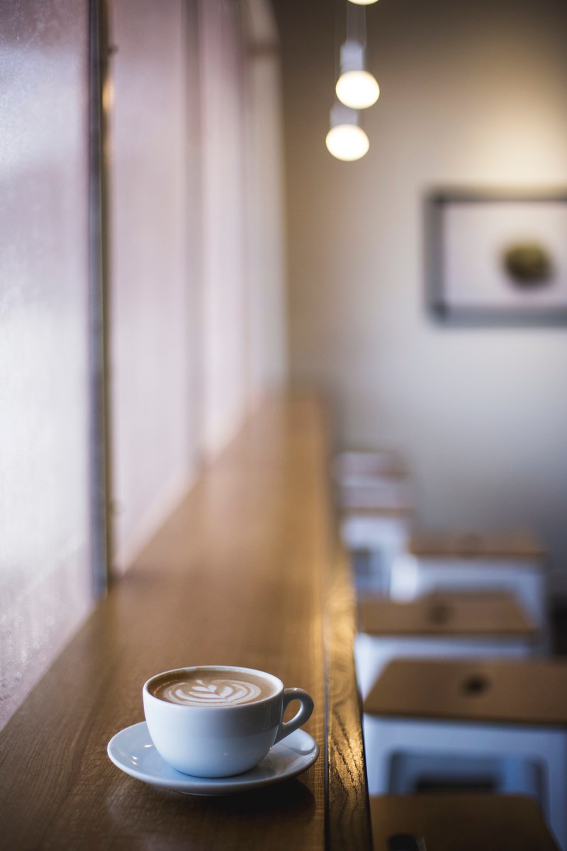 a cup of coffee with latte art on a sill at an empty coffee shop, crema nashville 4k