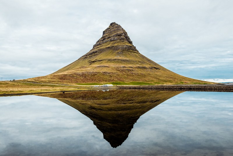 a free standing mountain reflected in the clear surface of a lake, kirkjufell mountain 4k