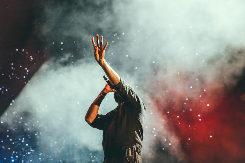 musician reaching out hand while singing on stage during a show, lead singer 4k