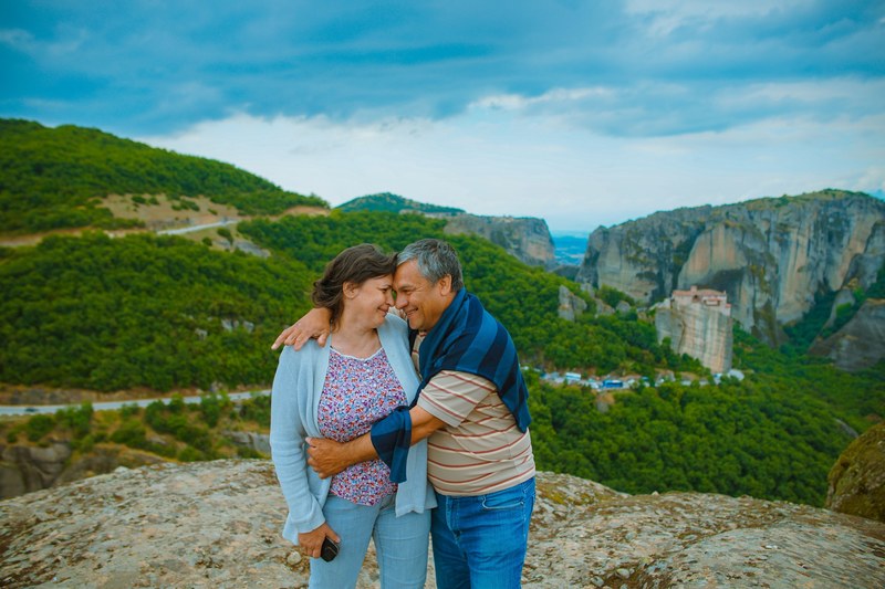 an older couple in a loving embrace above a valley in meteora, love lasts forever 4k