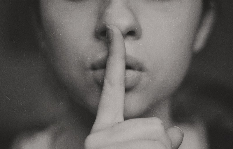a black and white shot of a woman putting a finger over her lips in a gesture of silence, secret 4k