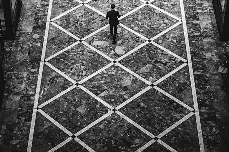 a male walking down a diamond patterned street, _walking on patterned road 4k