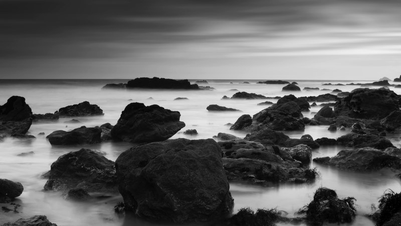 a black and white photo of rocks protruding from the ocean along the coast, monochrome coastal rocks 4k