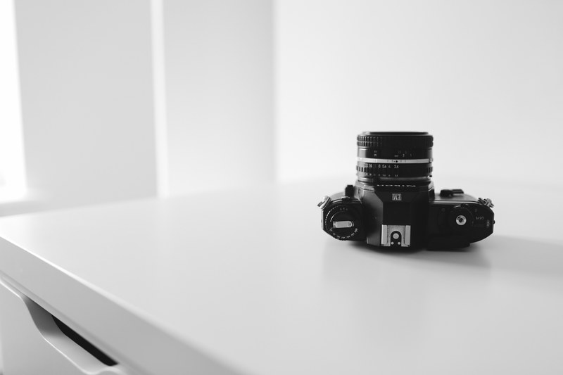 monochrome of a camera sitting upside down on a table top, monochrome camera on table 4k