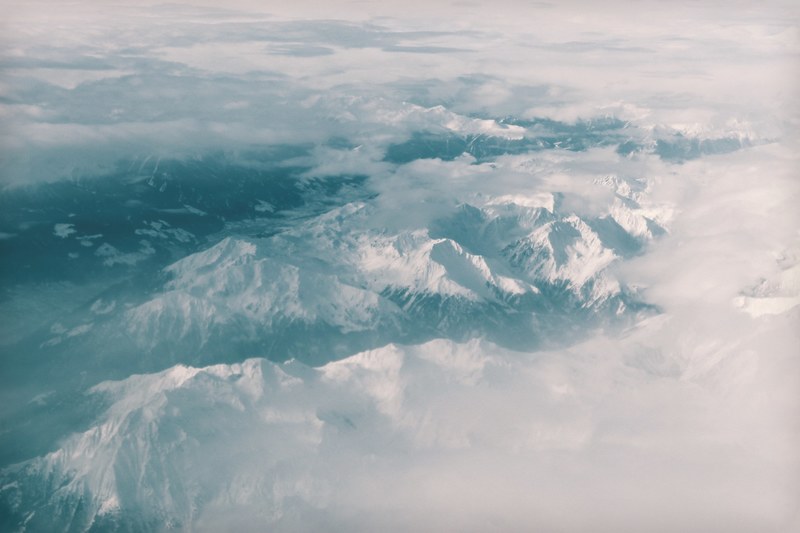 a drone view of the swiss alps snow covered mountains surrounded by fog, _snow covered swiss alps 4k