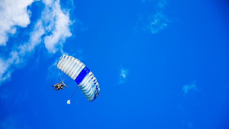 people tandem paragliding across a blue sky with soft clouds, tandem paragliding 4k