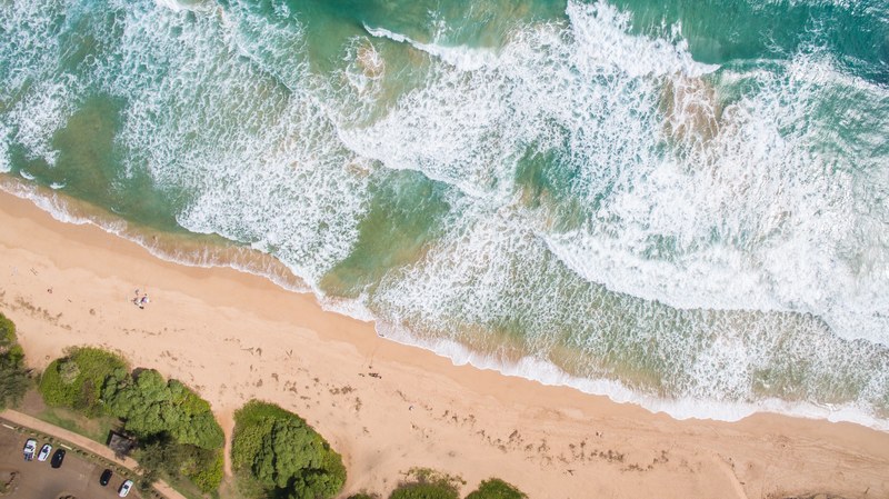 drone view of the ocean washing on the beach sand shore at kauai beach drive, drone view of ocean shoreline 4k