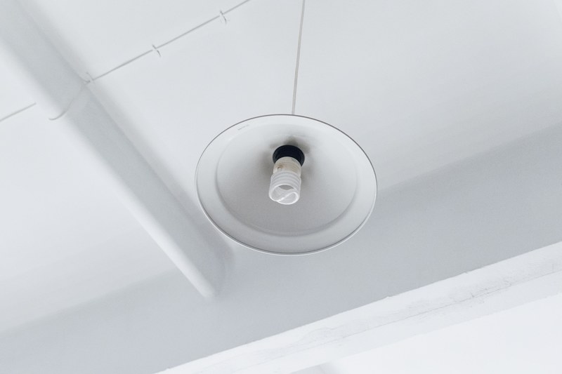 bottom view of light bulb in white hanging light near the corner of white room, bulb in white lamp and room 4k