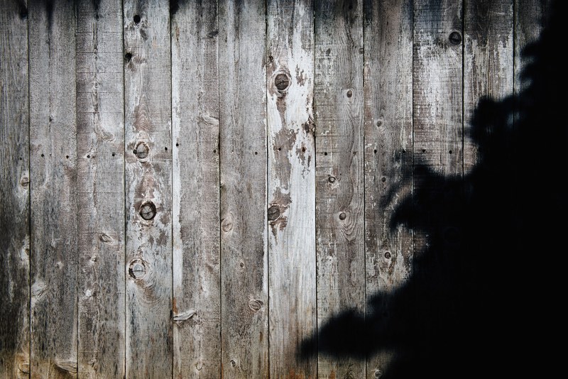 a black shade on a wooden plank wall, fenced in 4k