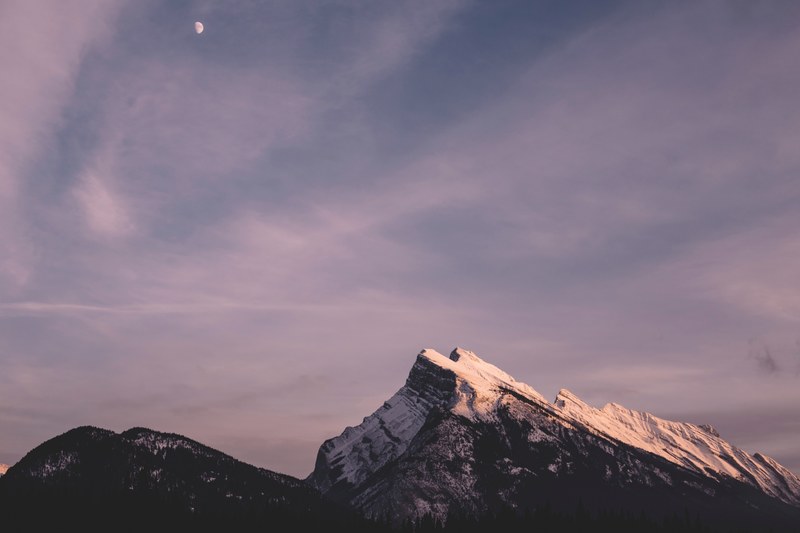 moon on a cloudy sky over the mountains at banff, moonrise 4k