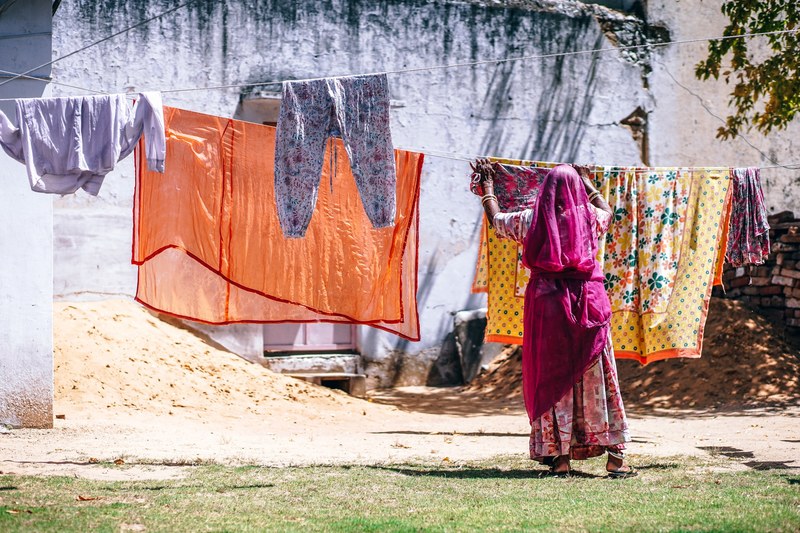 woman hanging colorful laundry on the line in pushkar, laundry duty 4k