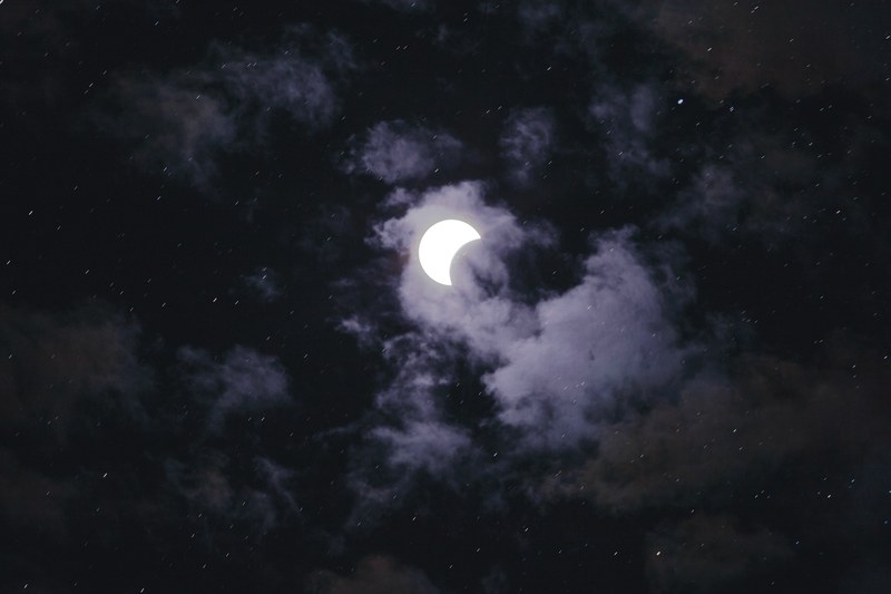 spooky crescent moon glows in a cloudy night sky, partial eclipse 4k