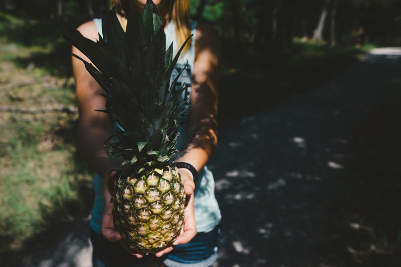 woman holding a fresh pineapple with a green top, pineapple 4k
