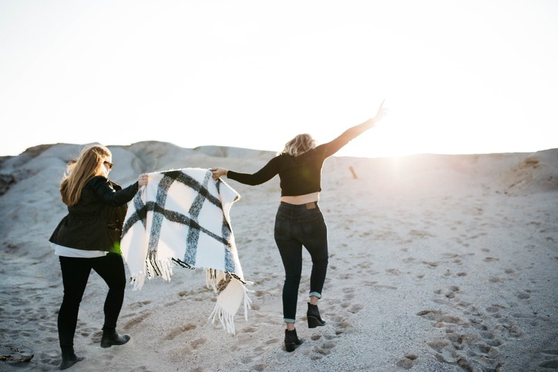 females in boots and jeans having fun holding a shawl in the sand with sunshine in joplin beach, females in jeans at joplin 4k