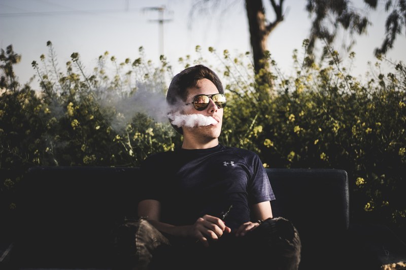 hipster man in sunglasses vaping and blowing smoke from his mouth, smoke 4k