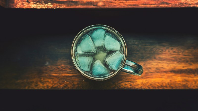 macro view of the top of a glass cup containing drink and ice, ice cubes 4k