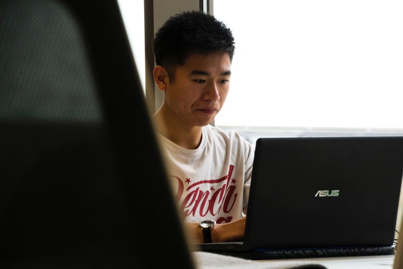 a young man sitting at a black laptop, developer at work 4k
