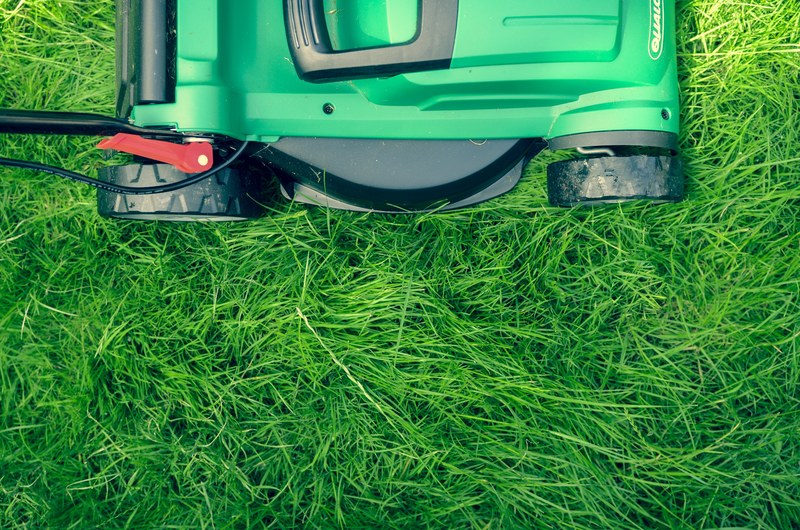 an overhead shot of a green lawnmower on green grass, mowing the lawn 4k