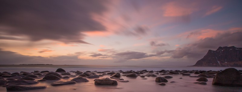 dusk over the beach with boulders on the shoreline of uttakleiv beach, rocky shore at uttakleiv beach 4k