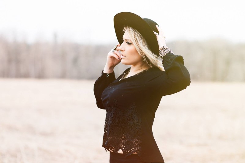 woman in a chic black outfit stands in a windy field, black country chic 4k