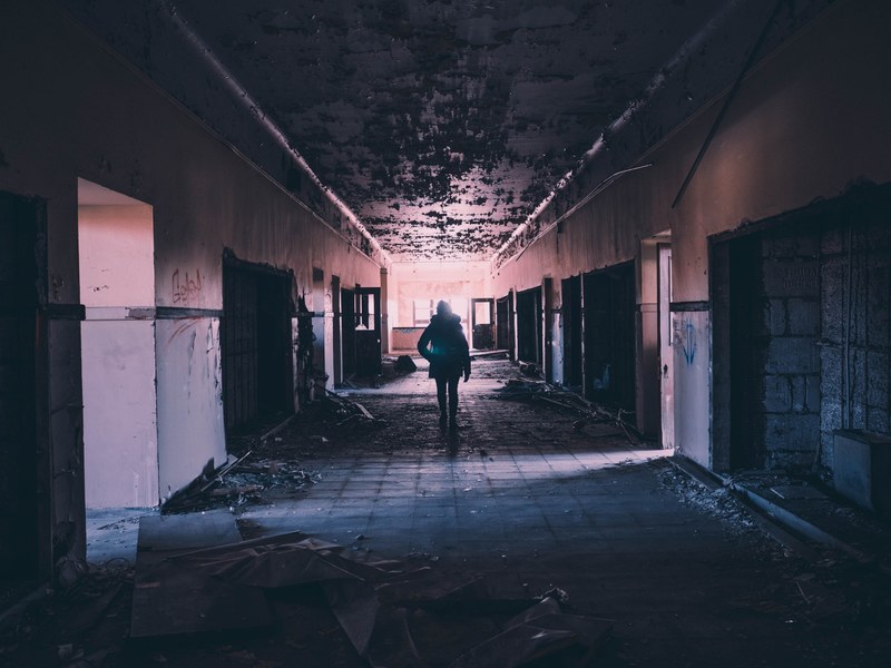 a person walking inside a dimly lit detroit building at night, detroit building at night 4k
