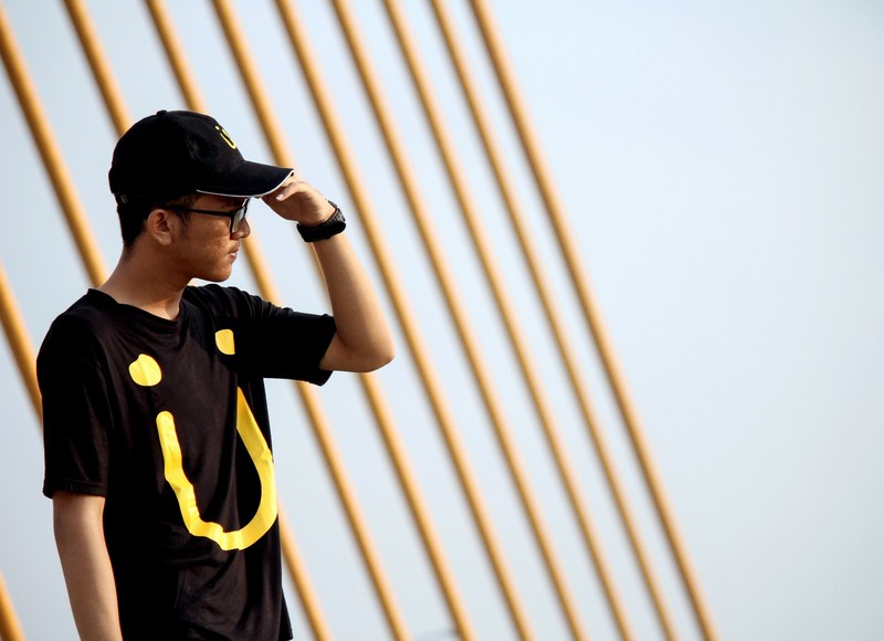 a man in a black cap and graphic t shirt by poles at adi sumarmo international airport, jack u 4k
