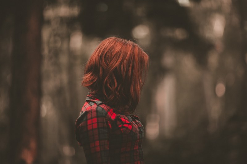 a woman with red hair obscuring her face in a plaid shirt against a blurry background, woman with red hair over face 4k