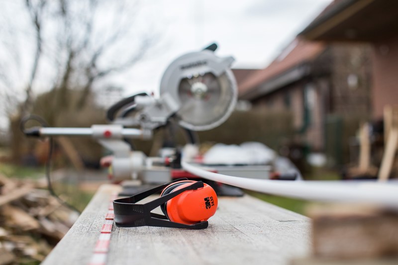 a pair of noise blocking earmuffs on a table near power tools, home renovations 4k