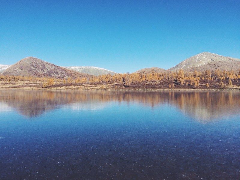 a clear lake surrounded by autumn trees and bare hills in russia, hills around a russian lake 4k