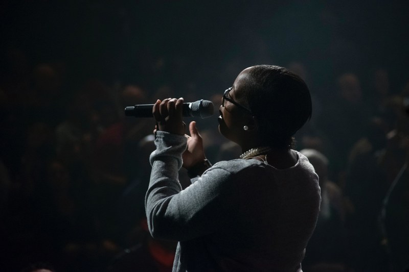 a woman singing into a microphone in a dim concert hall, female singers performance 4k
