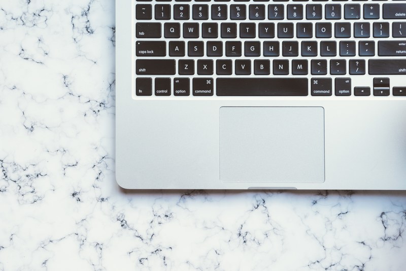 overhead shot of a macbook keyboard against white marble surface, minimal laptop keyboard 4k
