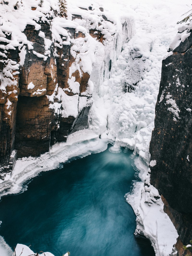 an icy mountain cliff is split by a frozen stream of water, an icy stream between cliffs 4k