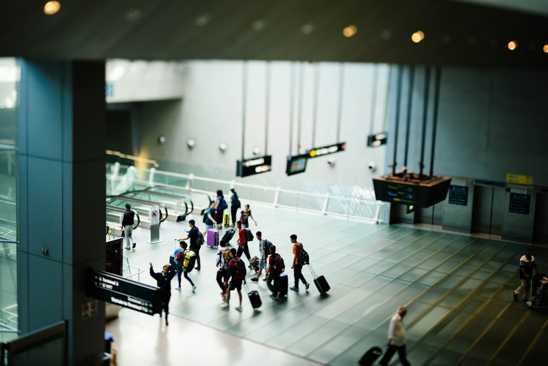 airport interior with travelers walking with suitcases towards escalators and information signs, airport interior travelers 4k