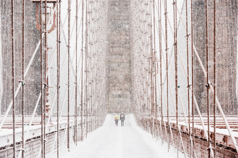 people walking across the brooklyn bridge during heavy snowfall, snowy brooklyn bridge 4k