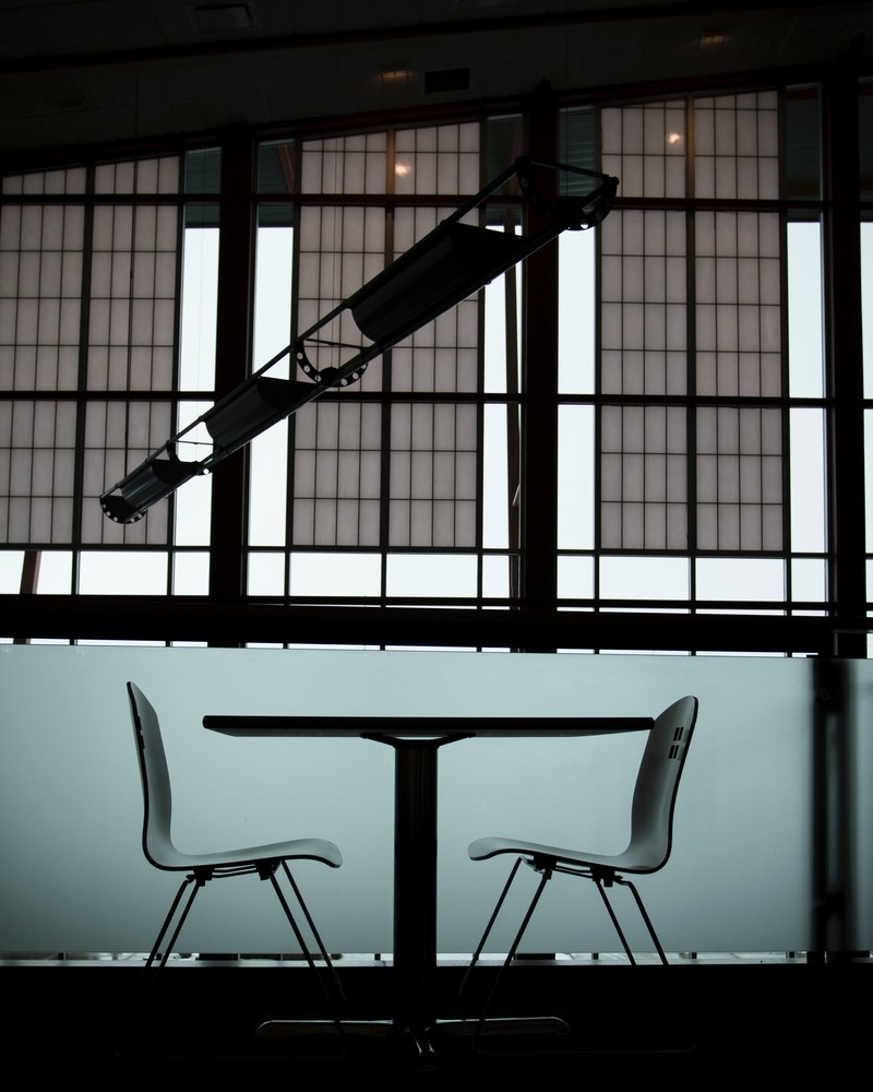 a side shot of a table with two chairs on in a cramped room, confession table 4k