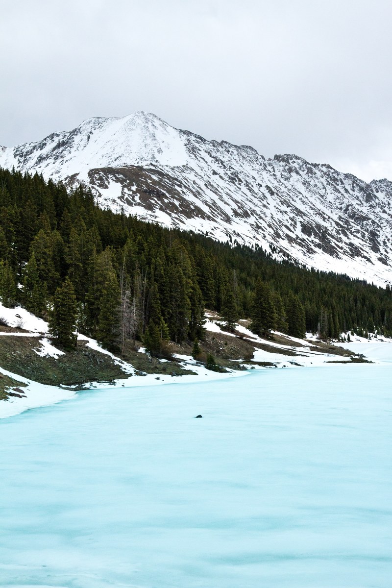 an icy blue half frozen lake in the mountains in summit county, tire in the lake 4k