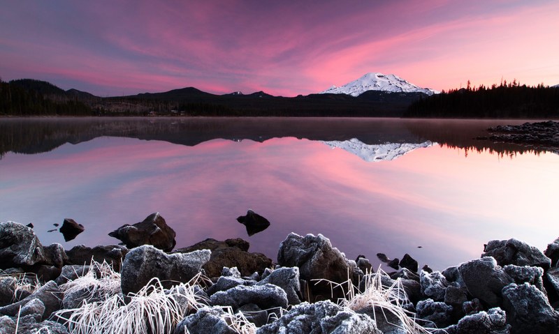 surreal pink sky reflects in still waters near a mountain landscape, open water during sunset 4k
