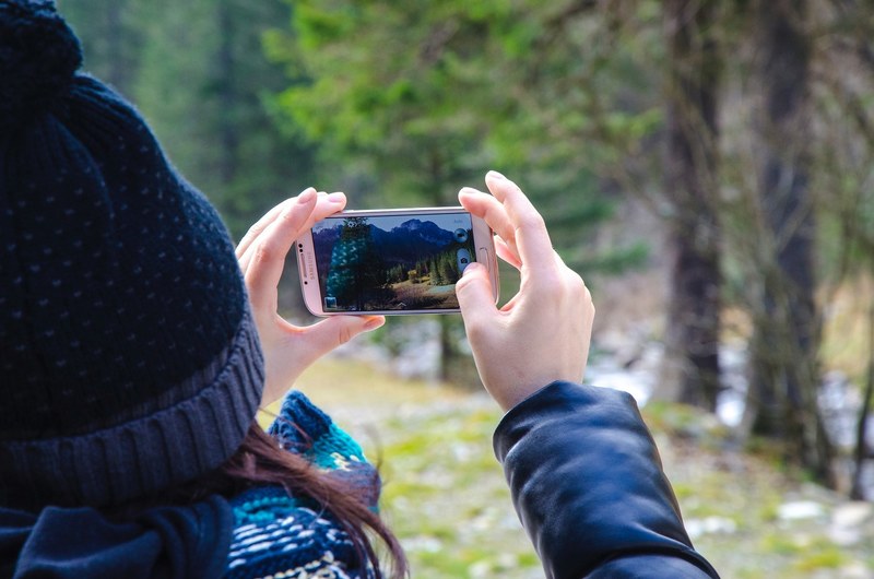 a woman taking a photo of the forest with an iphone cellphone, iphone cellphone photo 4k